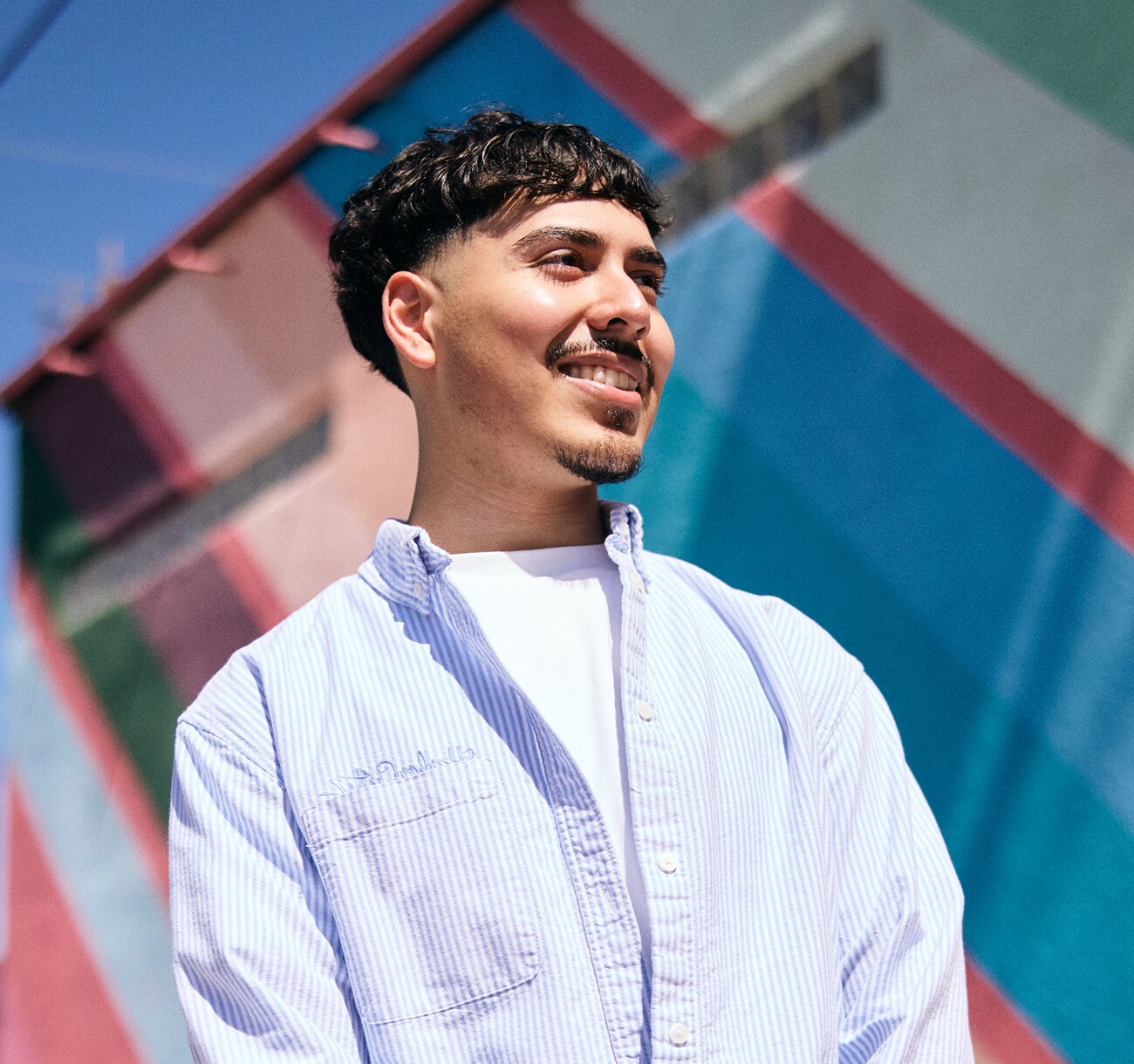 A student smiling in front of a school.