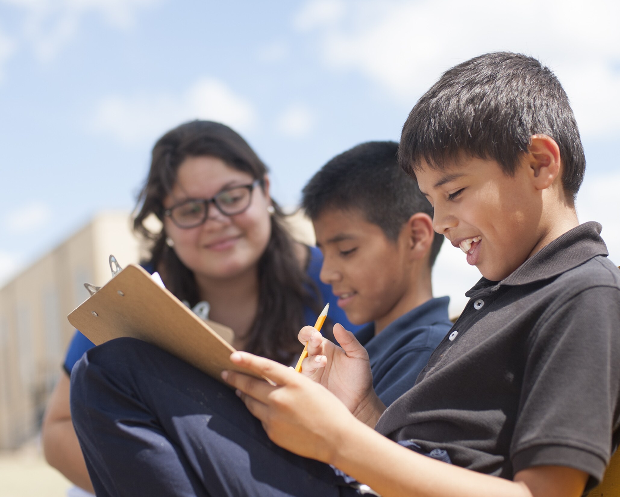 A teacher and students completing a worksheet outside.