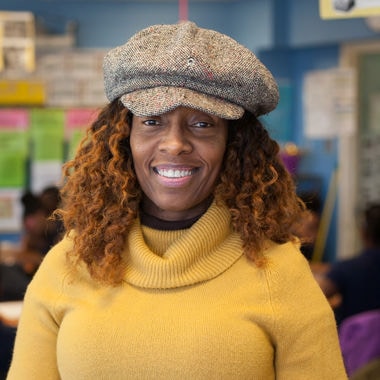 A female teacher stands in her classroom.