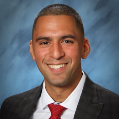 Head shot of man wearing suit and smiling.