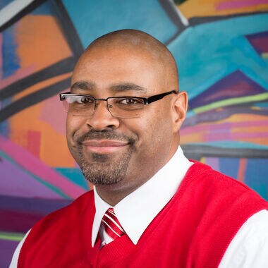 A man posing in front of a mural.