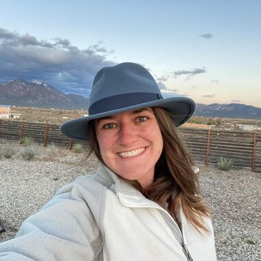 women wearing a grey hat and beige fleece smiling outdoors