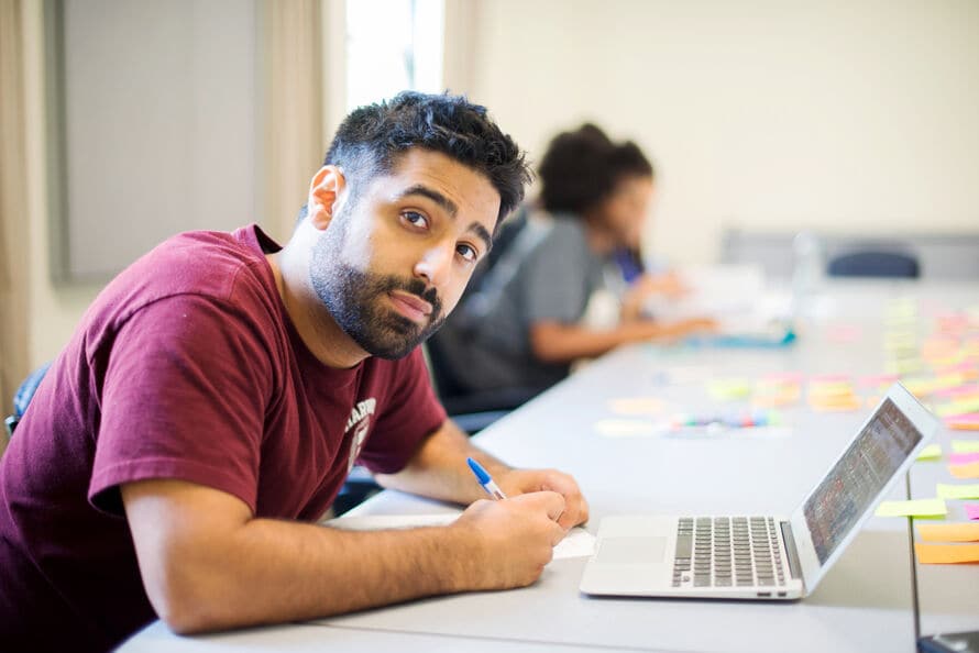 person taking notes while on computer