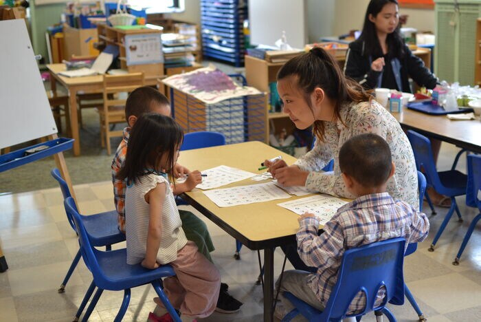 A Teach For America corps member working with a small group of young students.