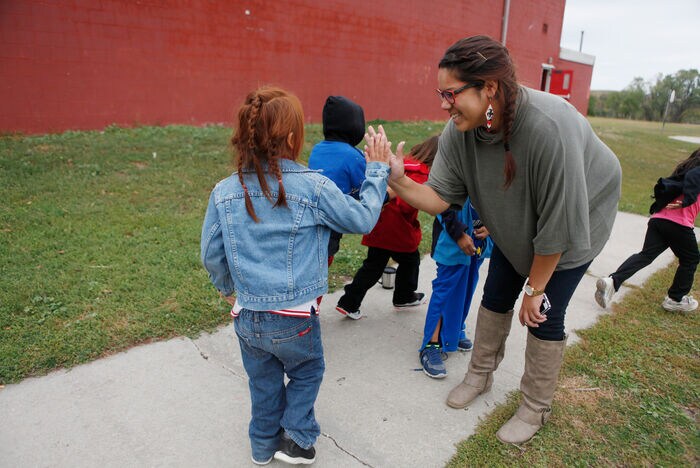 Mia Francis high fives students walking into South Dakota school. 