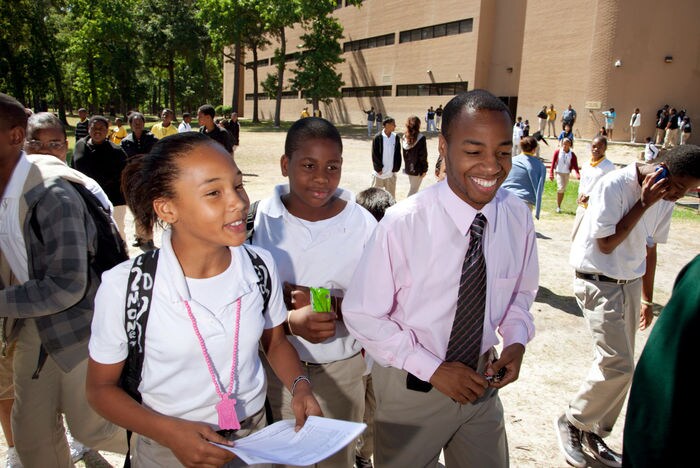 Corps member walking with students in courtyard of school.
