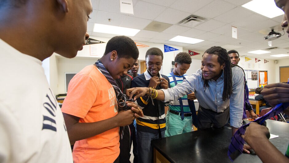 Justin Dunham (South Carolina '12) teaches middle school students how to tie ties in club he mentors. 