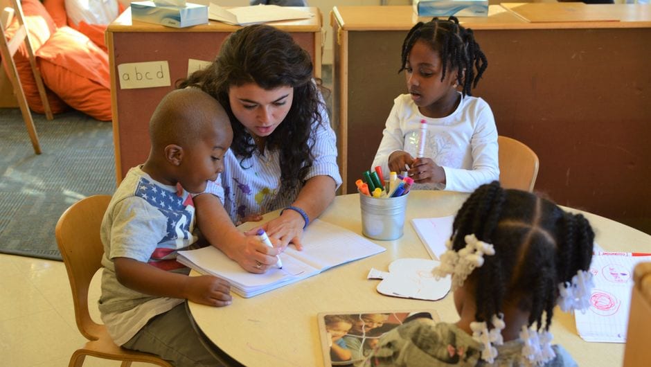 Teach For America teacher explains work to three students