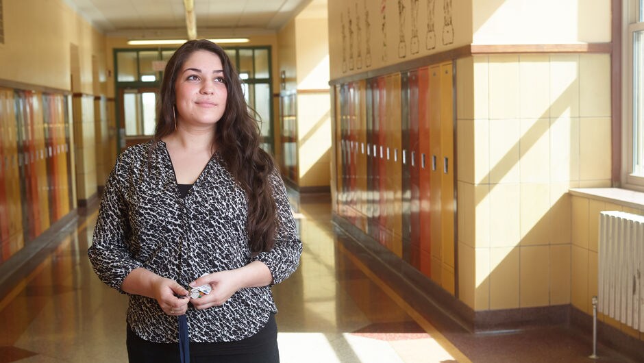 A teacher standing in a school hallway.