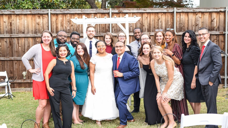 A group of friends gather around the recently married couple and pose for a photo