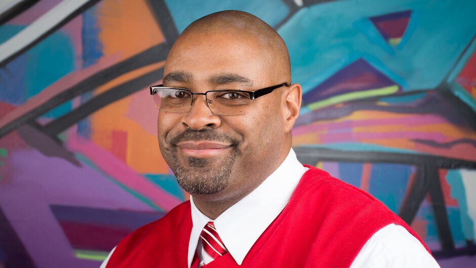 A man posing in front of a mural.