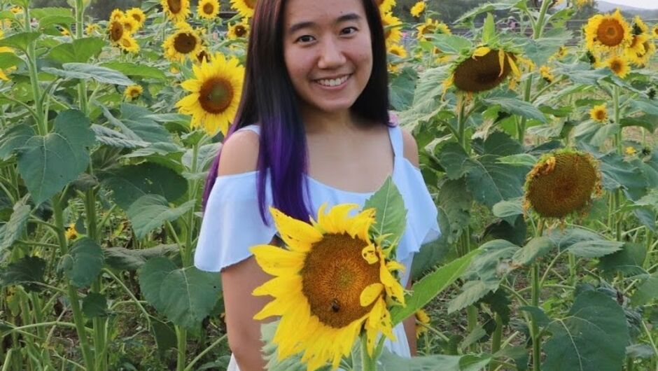 A photo of Serena Puang smiling in a field of sunflowers.