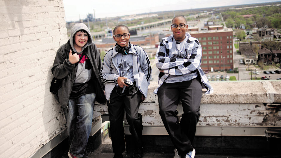 Three teenage students from Steel City Academy lean against a wall outside.