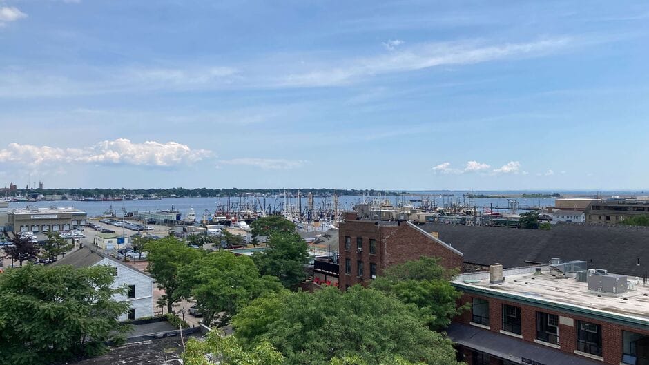 A scene of New Bedford, Massachusetts shows buildings and the coast.
