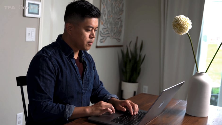 Tony DelaRosa sits at his desk, typing on his computer.