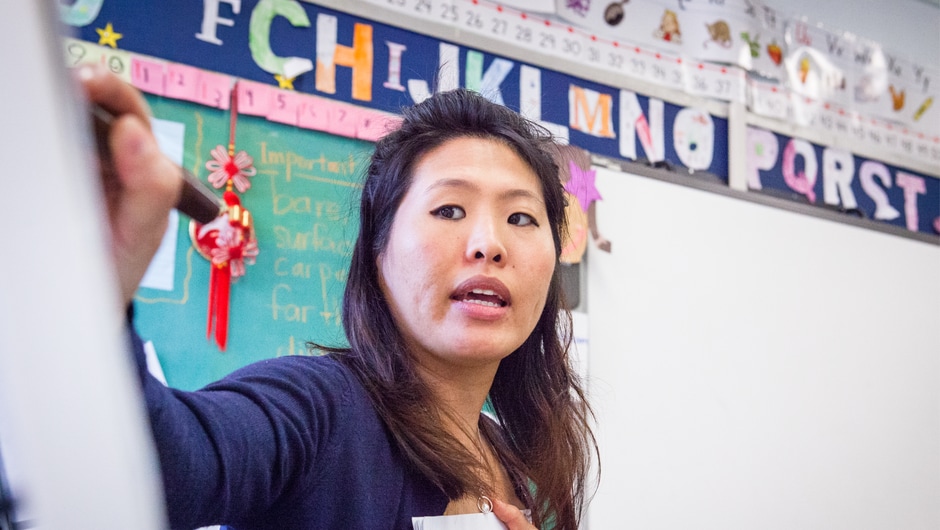 A female AAPI educator writes on a large paper pad easel. 