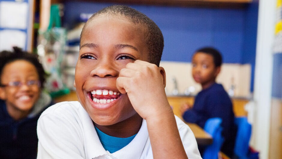 A student smiles in his classroom