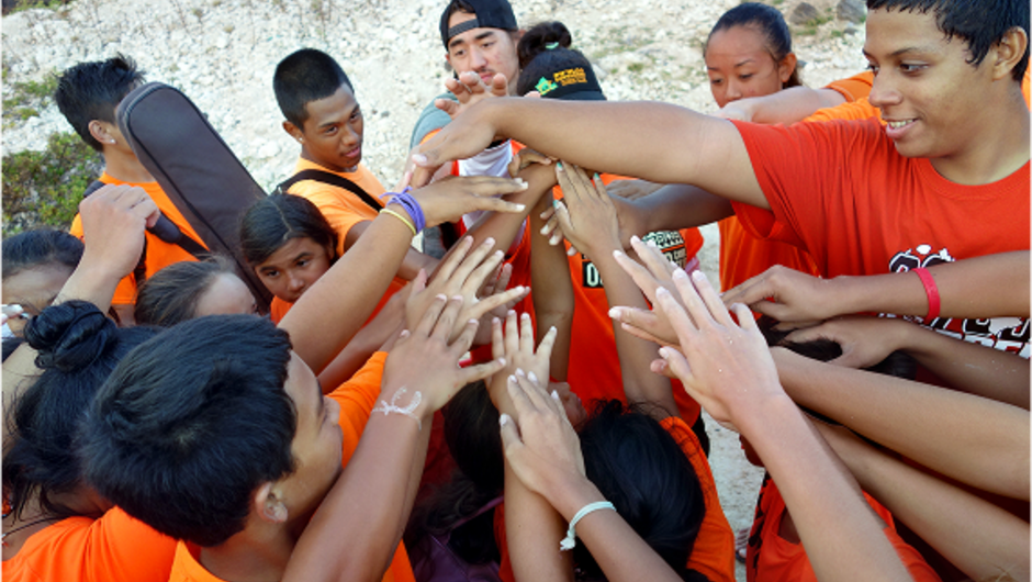 A circles of students putting their hands together