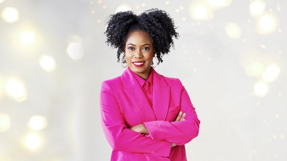 Charli Cooksey in a bright pink blazer standing in front of a white, sparkly background