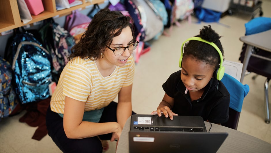A teacher works with a student in the classroom.