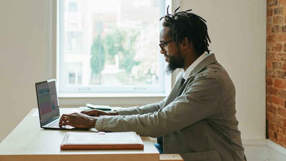 A young Black man working on a laptop.