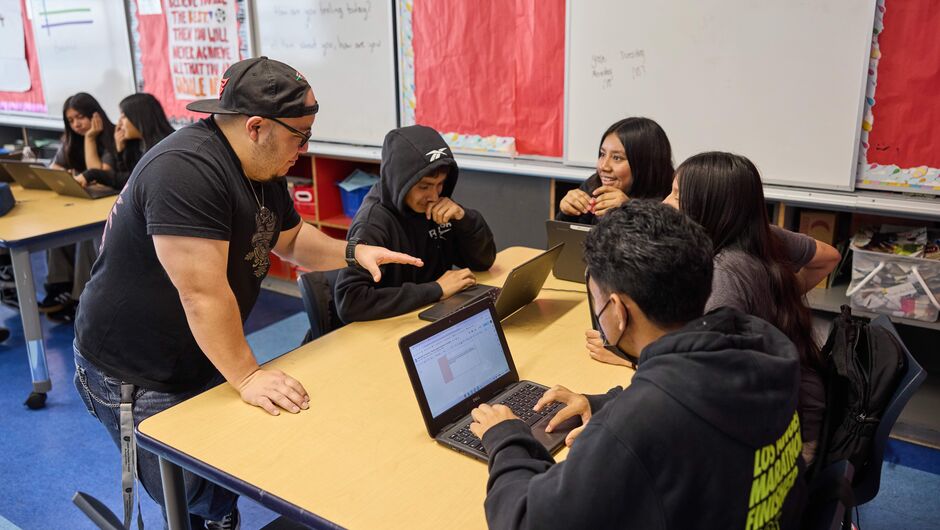 Teacher Mario Lopez works with students on computers.