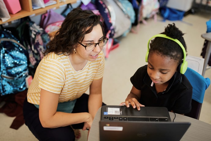A teacher works with a student in the classroom.
