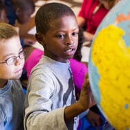 Students looking at a globe.