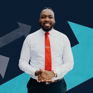 Kenneth Gorham stand hands folded with a white shirt, red tie and blue arrows behind him