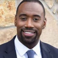 man smiling in front of a cement wall