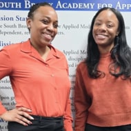 Dr. Roshone Ault Lee (left) and Deja Senghor (right) standing next to each other wearing red shirts