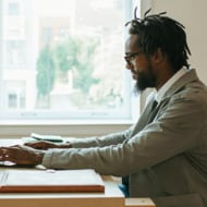 A young Black man working on a laptop.